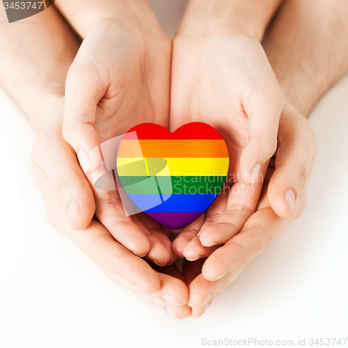 Image of male and female hands holding rainbow heart