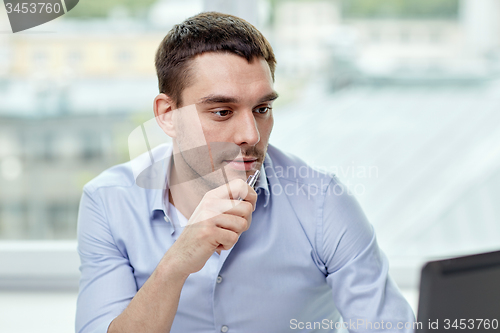 Image of young businessman with laptop computer at office