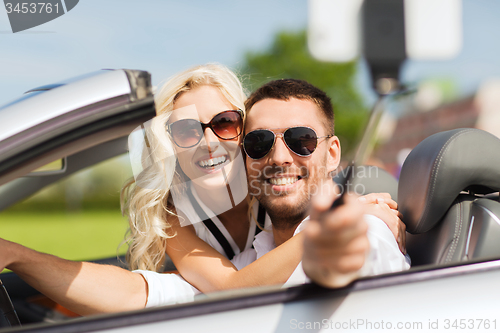 Image of happy couple in car taking selfie with smartphone