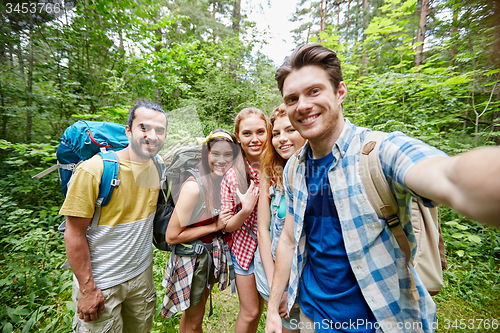 Image of friends with backpack taking selfie in wood