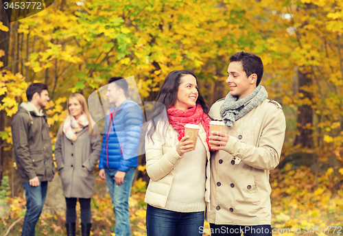 Image of group of smiling friend with coffee cups in park