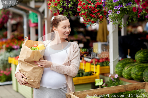 Image of pregnant woman with bag of food at street market