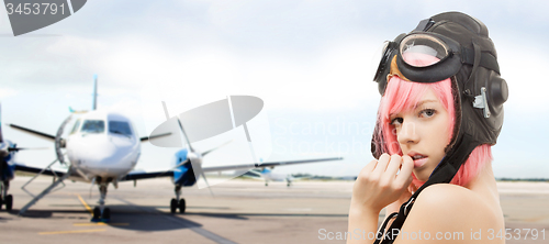 Image of girl in aviator helmet over plane at airport