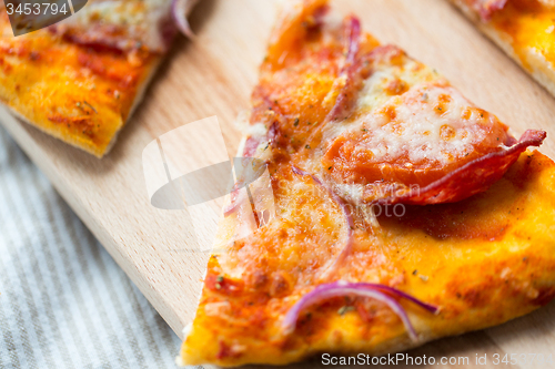 Image of close up of homemade pizza slice on wooden table