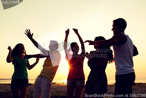 Image of smiling friends dancing on summer beach