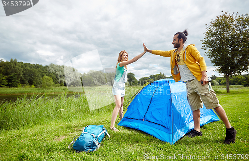 Image of happy couple setting up tent outdoors