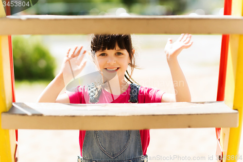 Image of happy little girl climbing on children playground