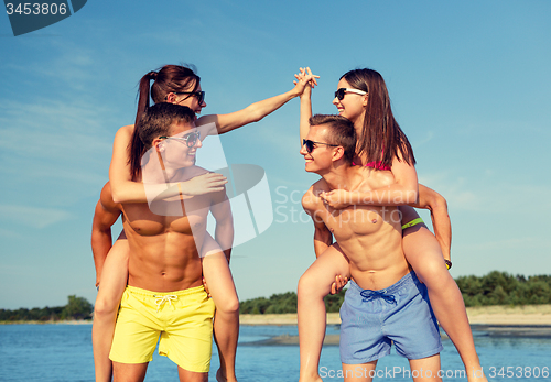 Image of smiling friends in sunglasses on summer beach