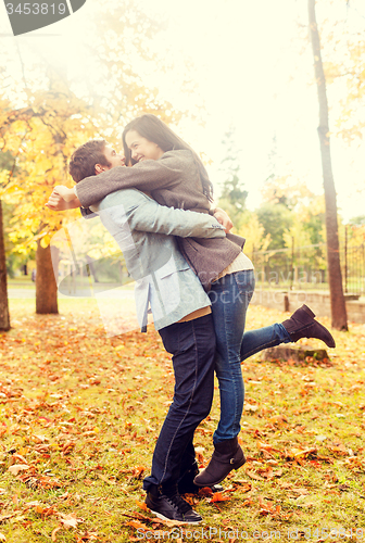 Image of smiling couple hugging in autumn park