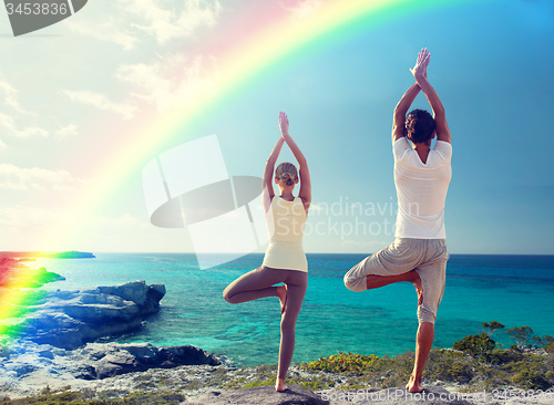 Image of young man making yoga exercises on summer beach