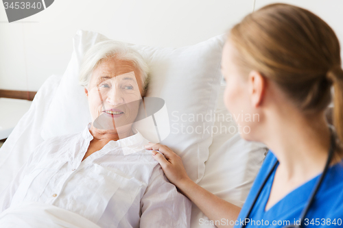 Image of doctor or nurse visiting senior woman at hospital