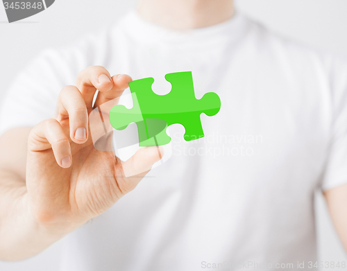 Image of close up of man holding green puzzle piece