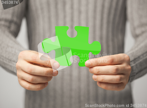 Image of close up of man holding green puzzle piece