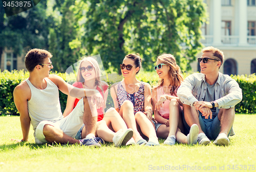 Image of group of smiling friends outdoors sitting on grass