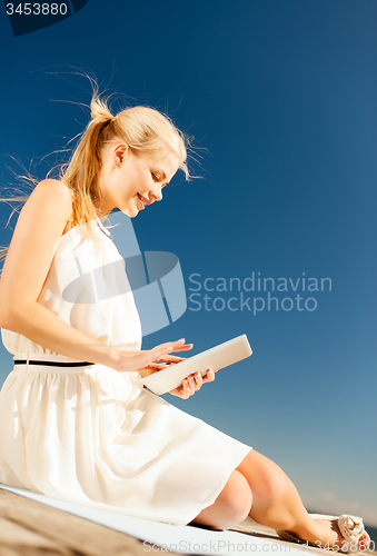 Image of beautiful smiling woman with tablet pc outdoors