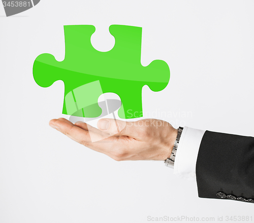 Image of close up of man holding green puzzle piece