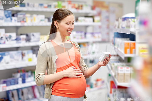 Image of happy pregnant woman with medication at pharmacy