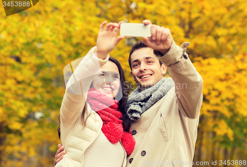 Image of smiling couple hugging in autumn park