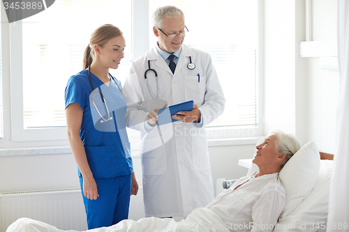 Image of doctor and nurse visiting senior woman at hospital
