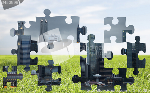 Image of puzzle of city over blue sky and grass background