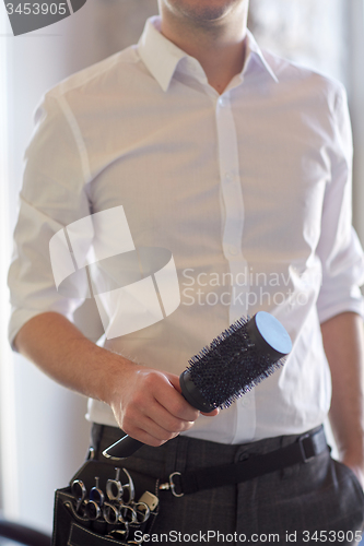 Image of close up of male stylist with brush at salon