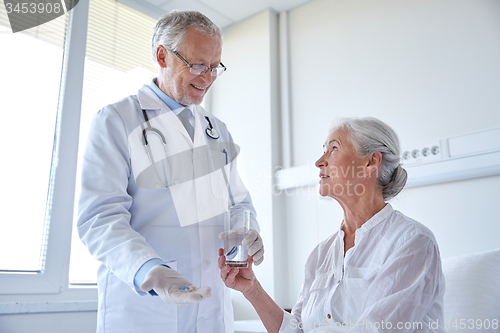 Image of doctor giving medicine to senior woman at hospital