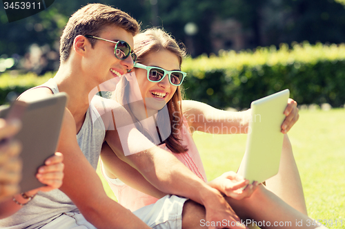 Image of smiling friends with tablet pc computers in park