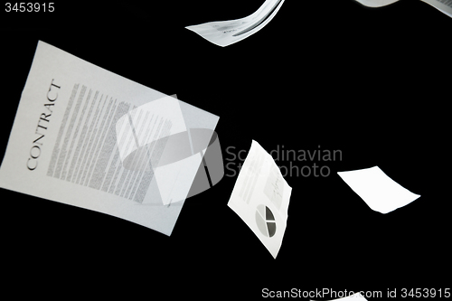 Image of business papers falling down over black background