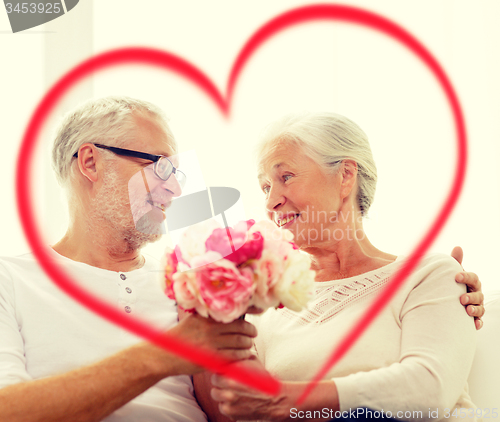 Image of happy senior couple with bunch of flowers at home