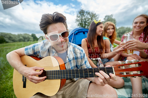 Image of happy man with friends playing guitar at camping