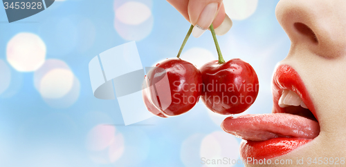 Image of woman mouth with lips and tongue eating cherry