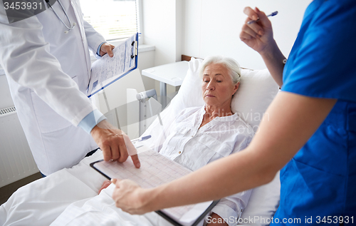 Image of doctor and nurse visiting senior woman at hospital