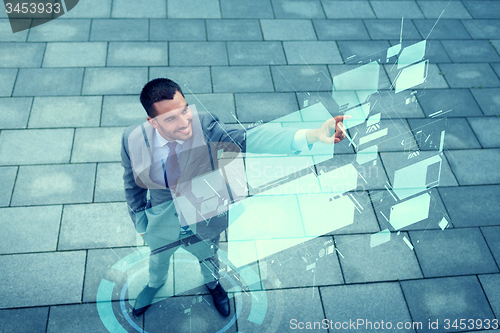 Image of smiling businessman with virtual screens outdoors