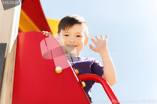 Image of happy little boy climbing on children playground