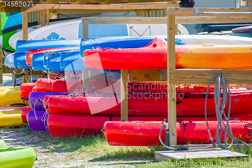 Image of set of kayaks laying on sandy beach on sunny day