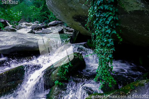 Image of river stream flowing over rock formations in the mountains