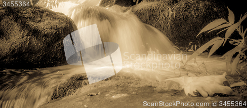 Image of river stream flowing over rock formations in the mountains