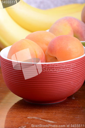 Image of bananas and apricots on red plate, close up