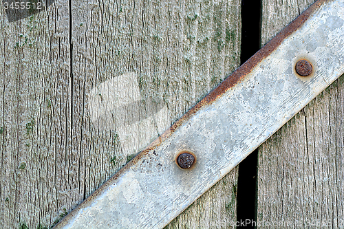 Image of Closeup head of big metal screw on wooden plate