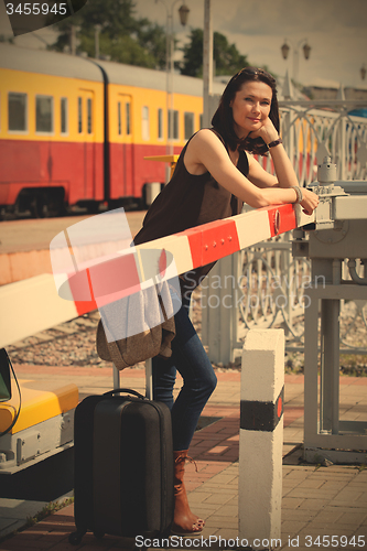 Image of woman traveler with a suitcase near the railway barrier