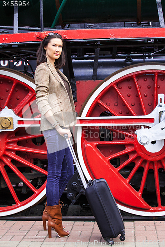 Image of woman with a suitcase near the huge locomotive wheels