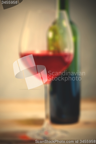 Image of red wine in glass and green bottle