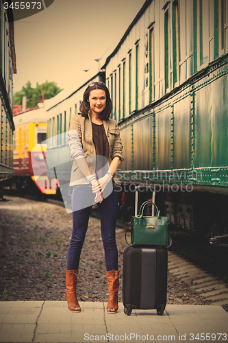 Image of pretty adult woman with a luggage near the train