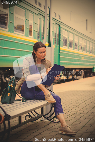 Image of beautiful adult woman takes notes in notepad