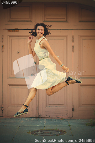 Image of beautiful brunette  jumped in a white dress
