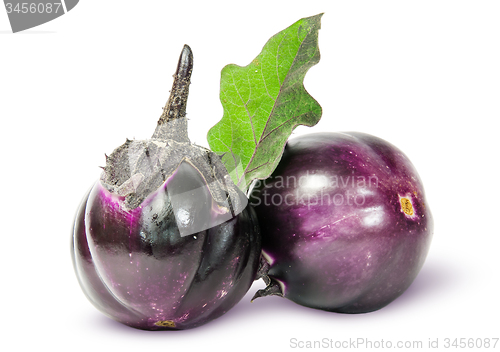 Image of Two round ripe eggplant with green leaf