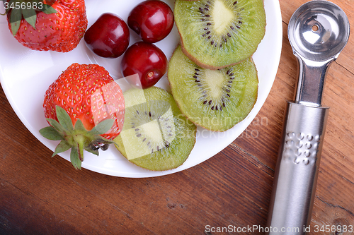 Image of fruit with cherry, strawberry, kiwi on wooden plate