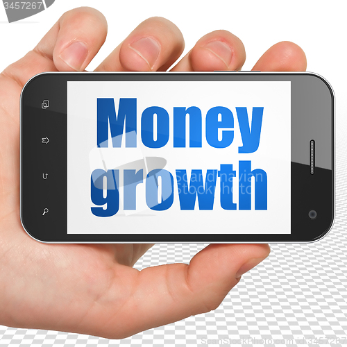 Image of Money concept: Hand Holding Smartphone with Money Growth on display