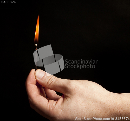 Image of Hand holding burning match stick