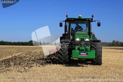 Image of John Deere 8370R Tractor on Field with Headlights on 